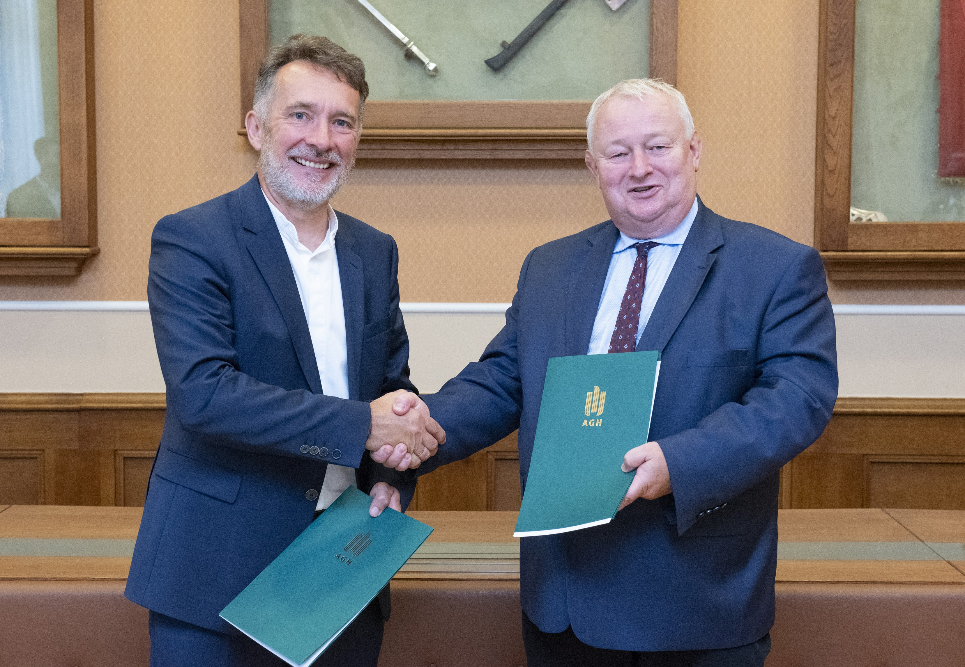 zdjęcie z podpisania współpracy z AGH, prof. dr hab. inż. Rafał Wiśniowski – Prorektor AGH ds. Współpracy i Krzysztof Noga – Prezes Zarządu Elenger Polska podają sobie dłonie trzymając dokumenty porozumienia